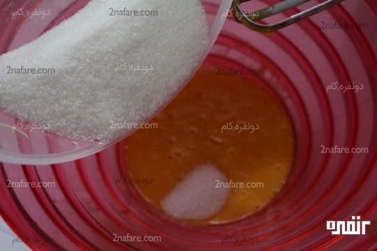 اضافه کردن ندریجی شکر به زرده های تخم مرغ زده شده