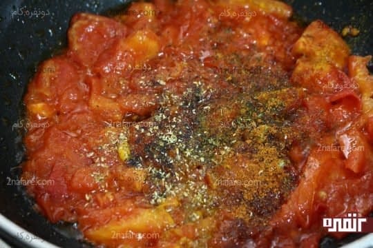 تفت دادن پوره گوجه فرنگی در روغن و اضافه کردن ادویه ها