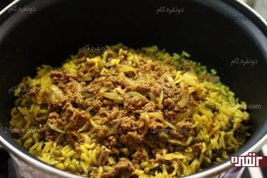 ریختن یک لایه از مخلوط گوشت چرخکرده روی پلو ماش