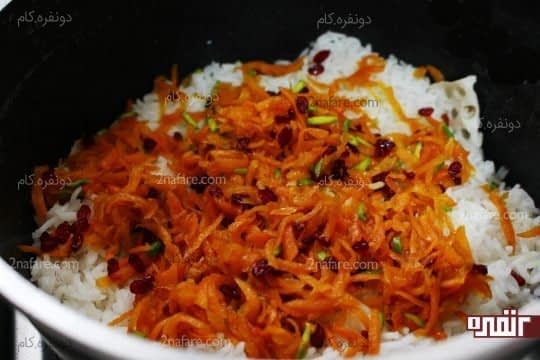 ریختن یک لایه از مخلوط هویج و زرشک و پسته روی برنج