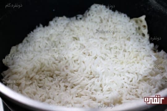 ریختن یک لایه برنج نیم پز کف قابلمه