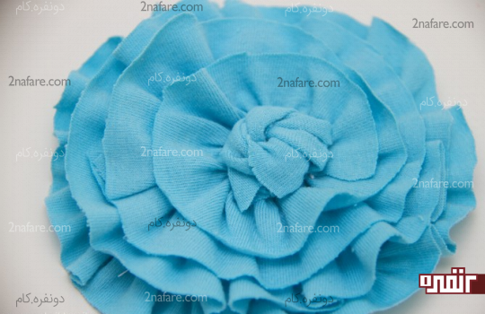 بریدن پارچه اضافی دور گره و چسبوندن وسط گل پارچه ای