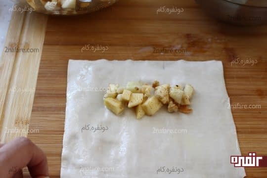 ریختن یک قاشق از سیب های مزه دار شده روی ورقه یوفکا