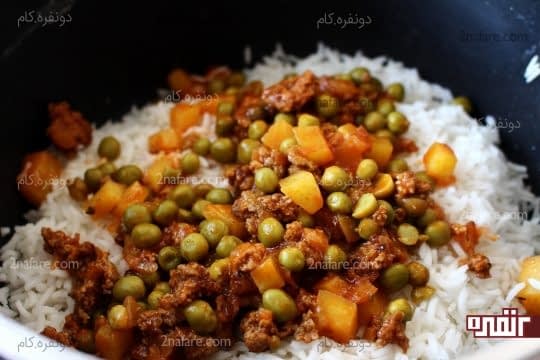 ریختن یک لایه از سس گوشت و نخود فرنگی روی برنج ابکش کرده