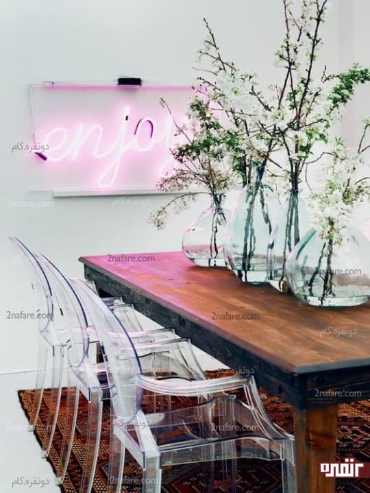 کنتراست بین میز چوبی غذاخوری با صندلی ها، اکسسوری های شیشه ای و نوار نئونی صورتی رنگ